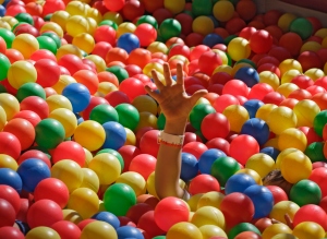 Child reaching up through sea of balls, close-up of arm